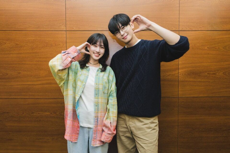 atores-do-dorama-the-wonder-fools-em-foto-promocional-fazendo-gesto-de-coração-com-as-mãos-em-frente-a-parede-de-madeira